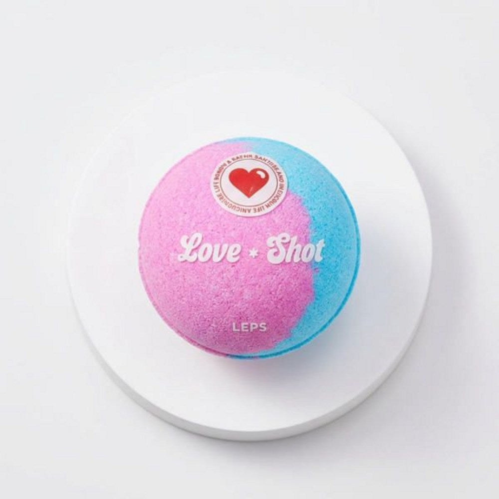 Love Shot bath bomb gift set detail showing one pink and blue round bath bomb on a white circular display