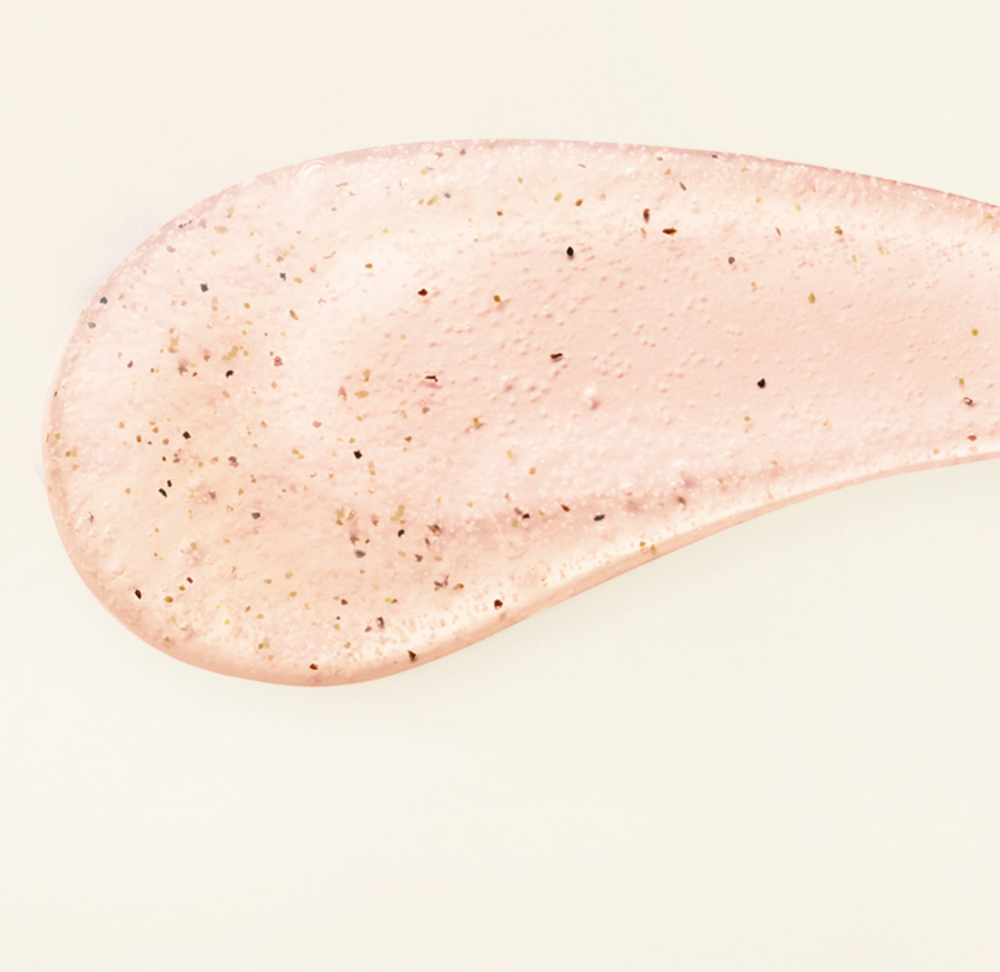 Veilment Black Rose scrub body wash texture shown as a translucent pink smear with scattered dark particles