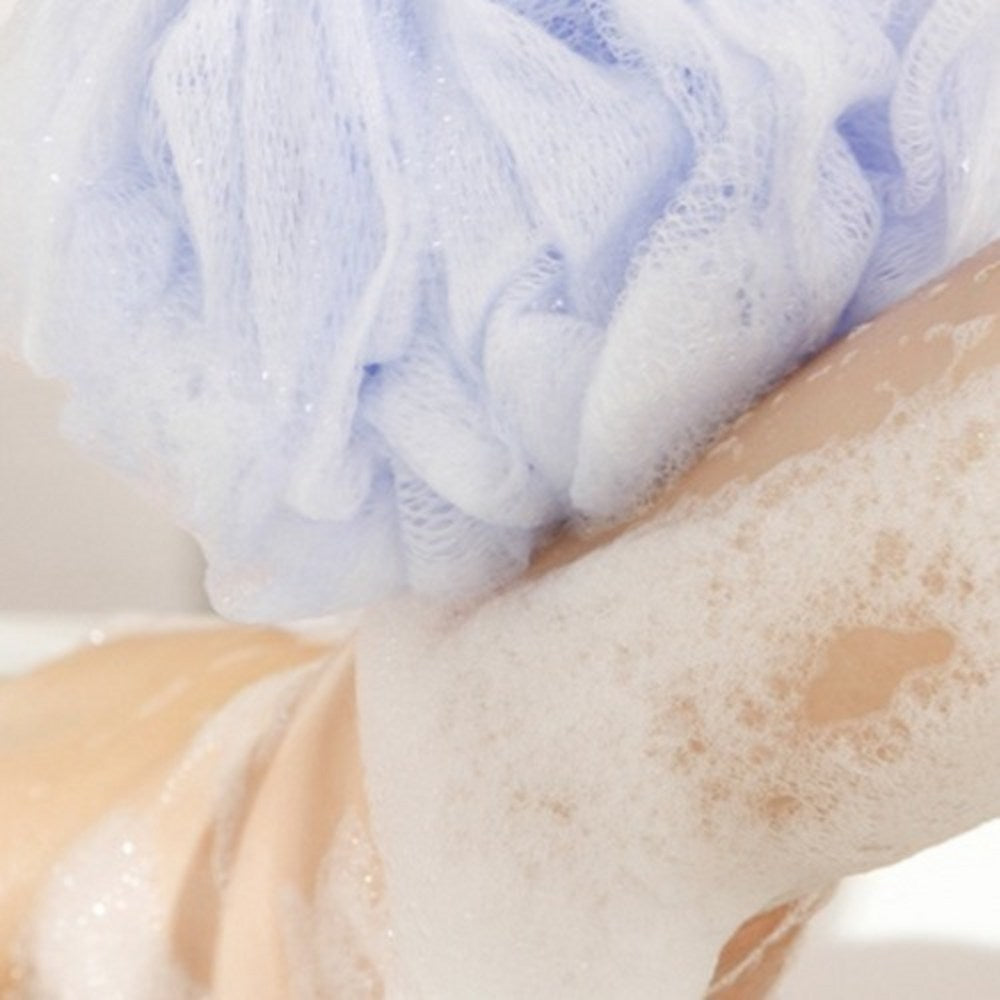 Veilment Black Rose scrub body wash lather on wet skin beneath a pale mesh shower sponge