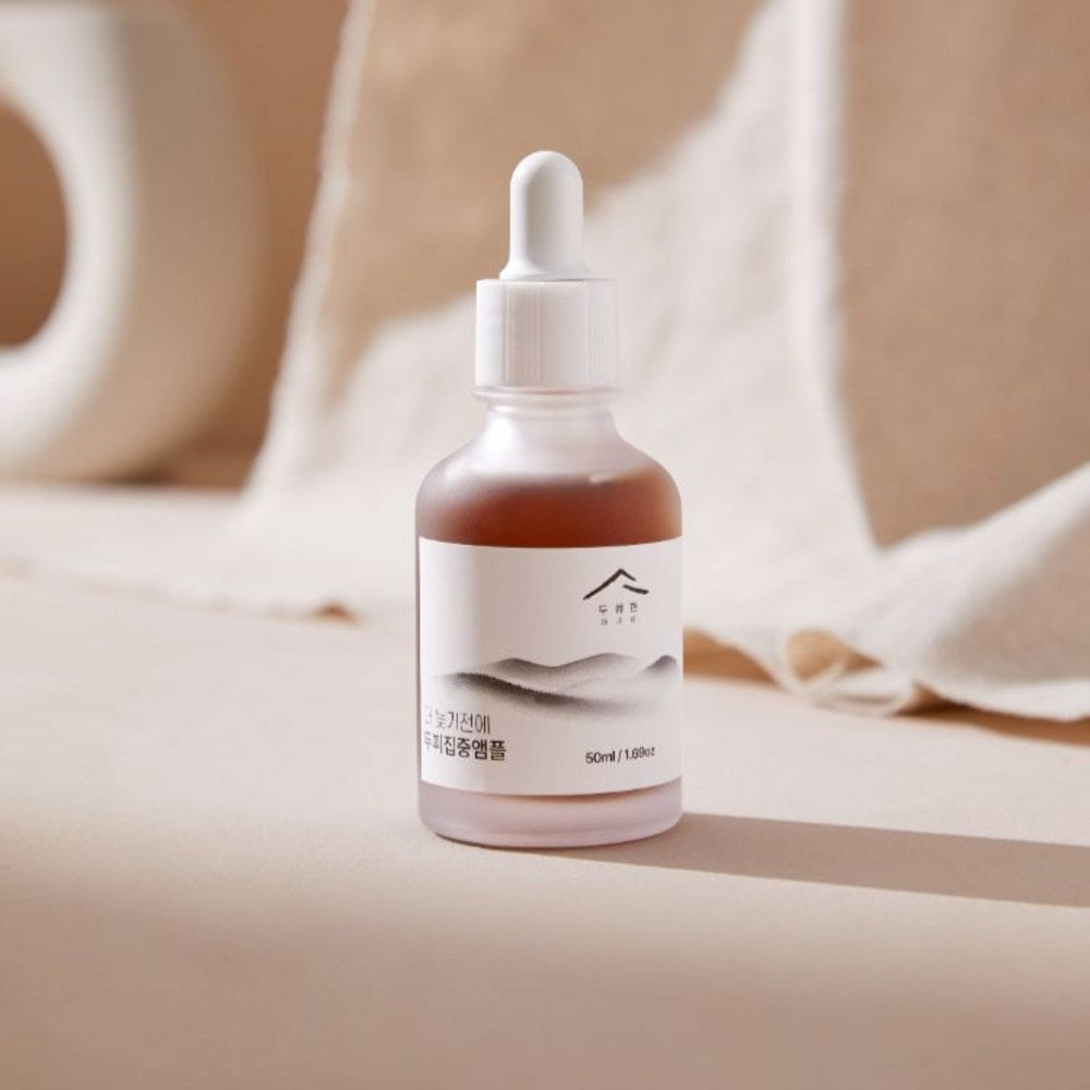 Dooryuheon scalp ampoule bottle on a beige surface, with a white dropper and soft fabric in the background