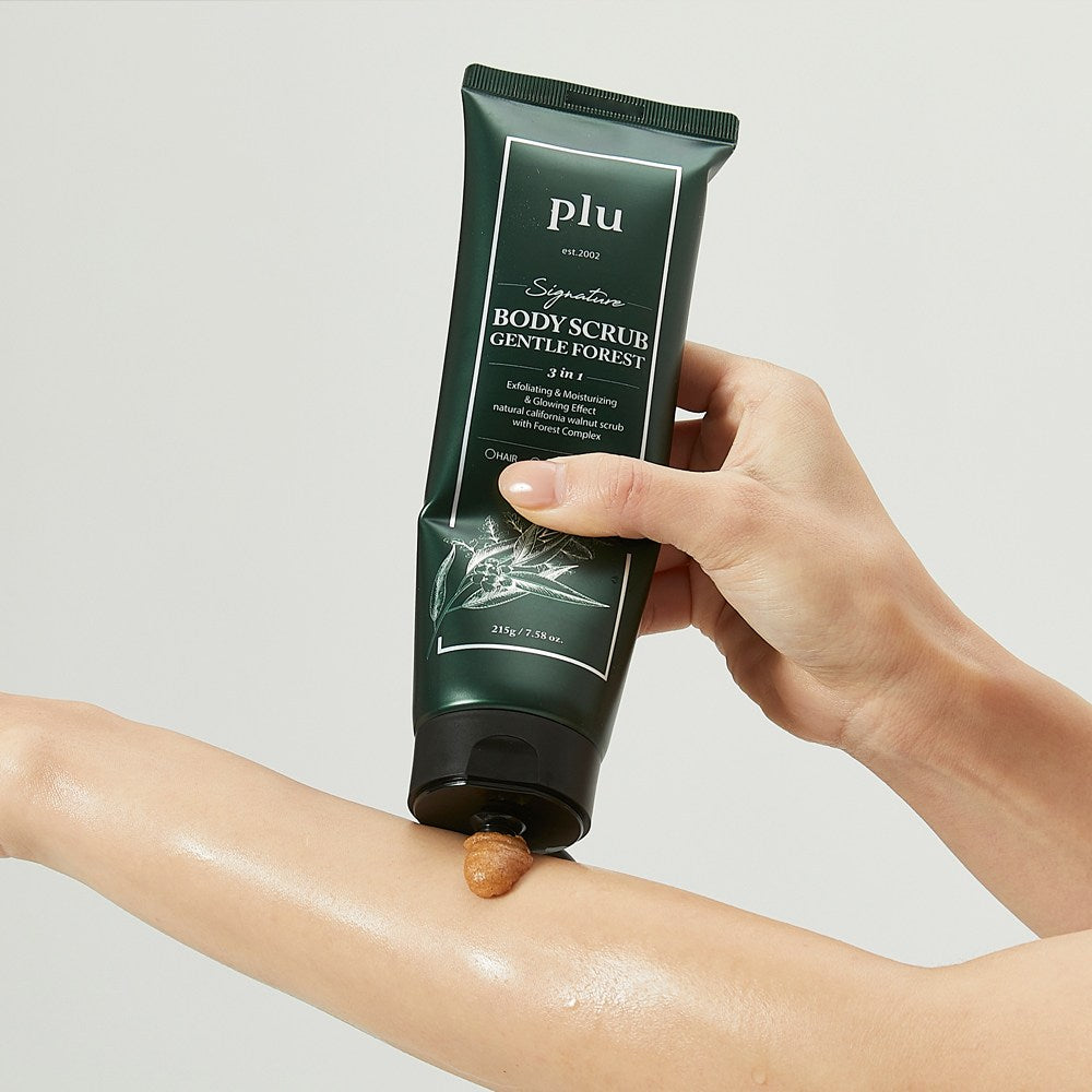 PLU Gentle Forest body scrub being squeezed from its dark green tube onto a wet forearm