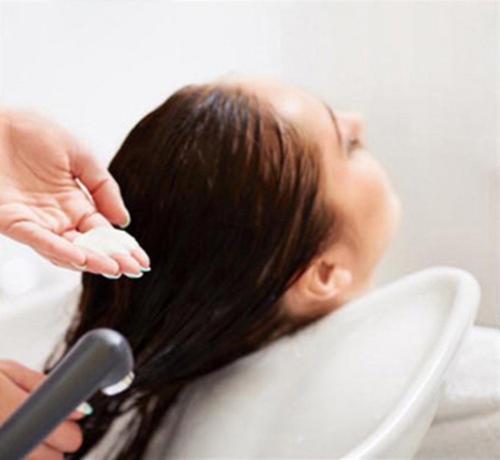 Bathcharm lavender bath salt promotional scene showing hair being rinsed at a salon basin beside a hand holding salt