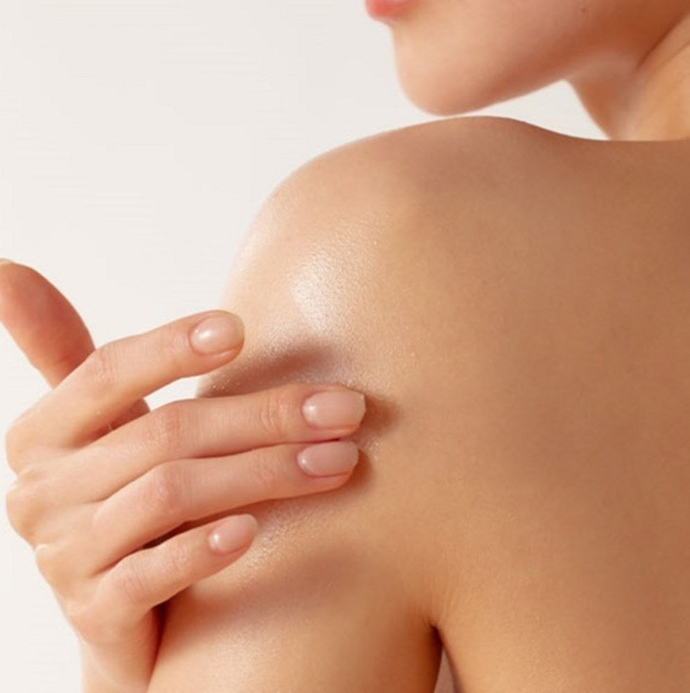 PLU body scrub wash lifestyle photo showing a hand resting on a bare shoulder against a pale background