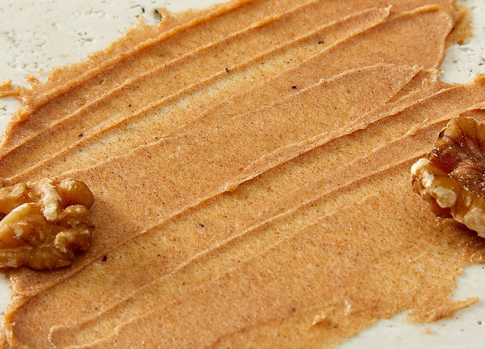 PLU Gentle Forest body scrub texture spread in broad brown streaks with visible grains and walnuts