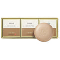 OSEQUE yellow clay soap with an embossed beige bar in front of three boxes in a gold-edged tray