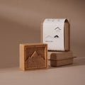 Dooryuheon Hinoki Cypress Soap with a brown, flecked mountain relief beside kraft packaging on a beige surface