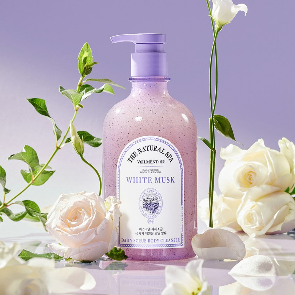Veilment White Musk body wash surrounded by white roses, green stems and petals against a lavender backdrop