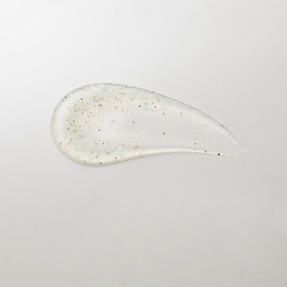 Veilment White Musk body wash texture spread on a pale surface, with small coloured scrub particles visible