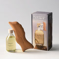 Aromatica body oil ritual set with a yellow oil bottle, curved wooden dolphin gua sha and lavender-labelled box