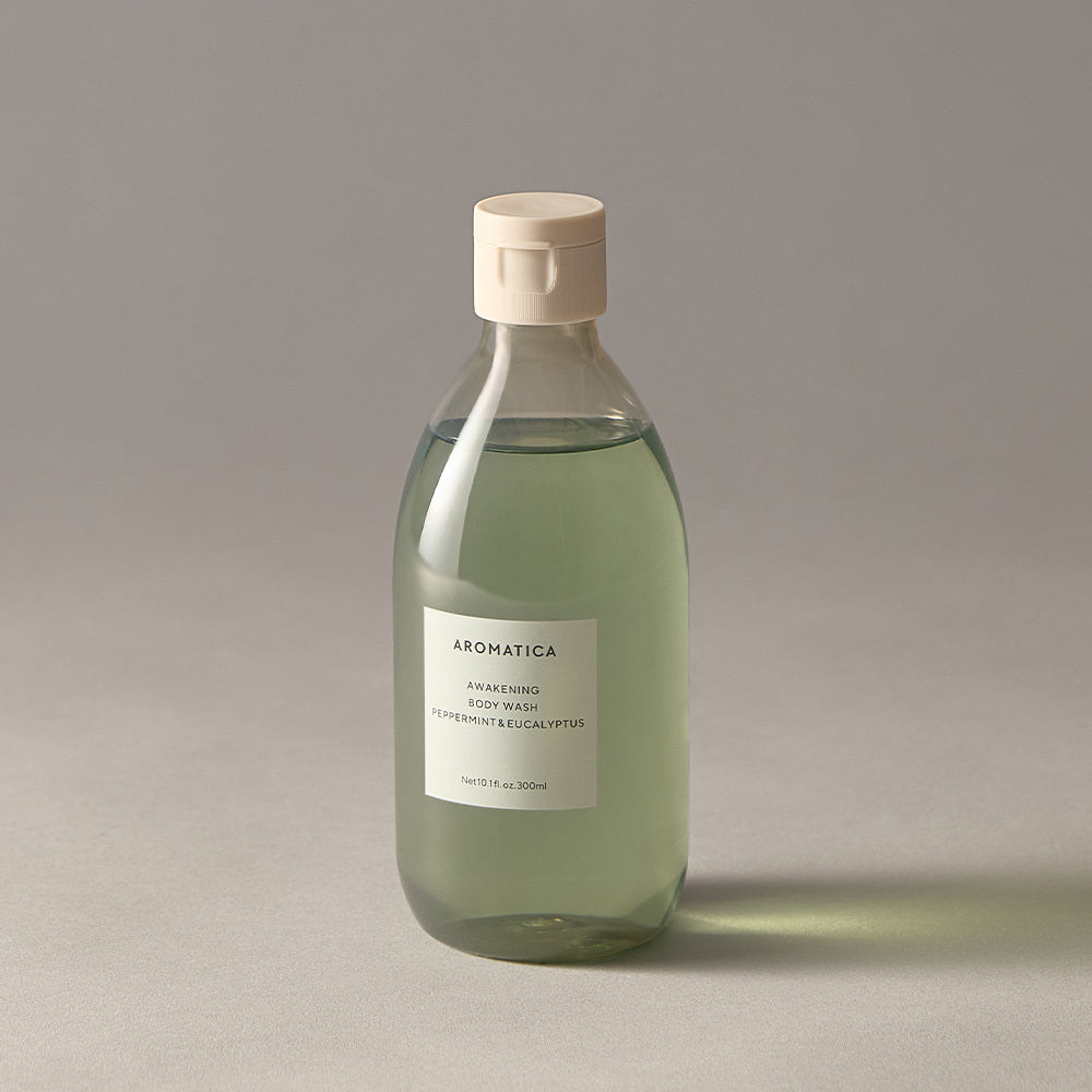 Aromatica Awakening body wash in a clear 300ml bottle with pale green liquid and a cream cap on a grey surface