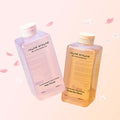 Round Around Scented Bubble Shower and Bath bottles in pale lavender and amber against a pink floral backdrop