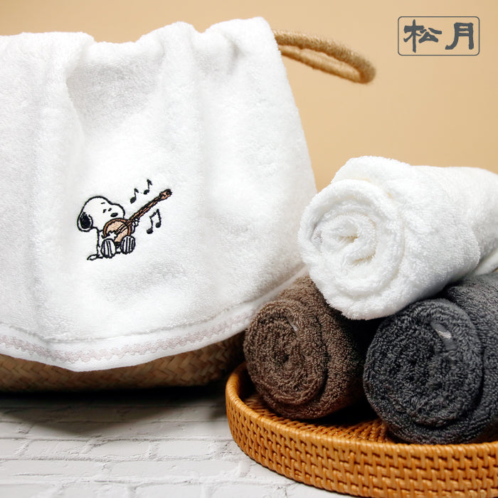 Songwol Snoopy solid face towels with ivory draped over a basket and ivory, brown and gray towels rolled in a tray