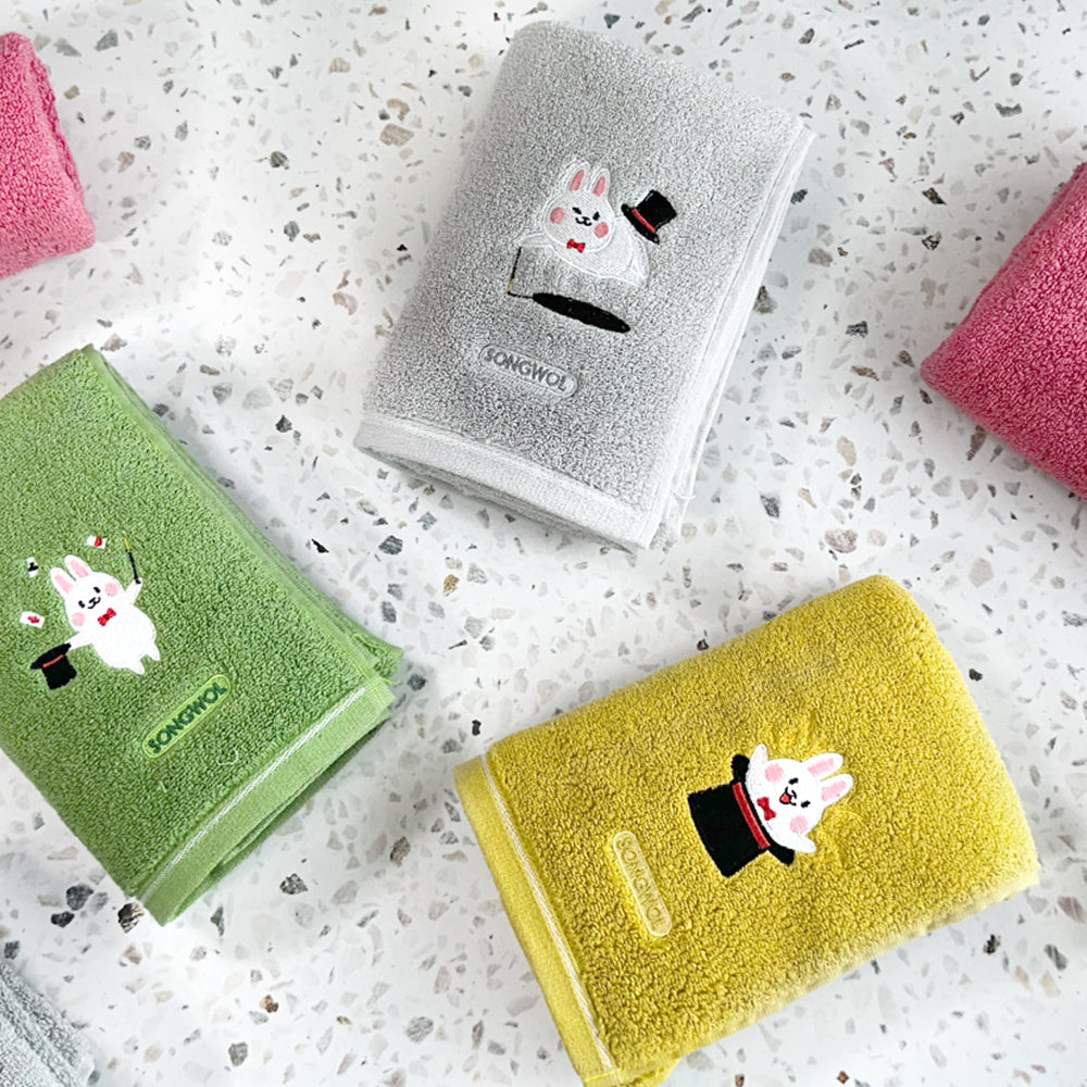 Songwol rabbit face towel set arranged on terrazzo, with grey, green and yellow towels showing different rabbits