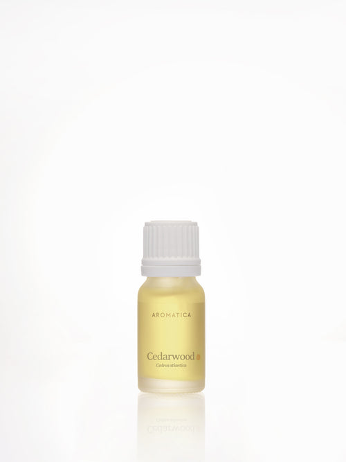 Aromatica Cedarwood essential oil in a yellow-toned bottle with a white ribbed cap and a reflection beneath it