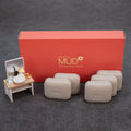 Boryeong Mud soap bars in a muted beige-grey shade beside a red branded box and a miniature washbasin prop