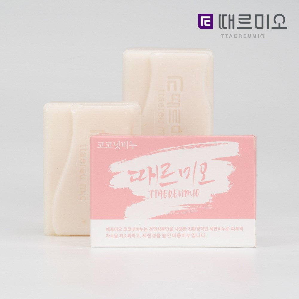 Ttaereumio coconut soap bars shown unwrapped behind a pink box, with lettering embossed on the pale soap
