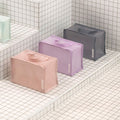 Travelers mesh wash bag in peach, lilac and grey, showing cube shapes, zip closures and handles on tiled steps.