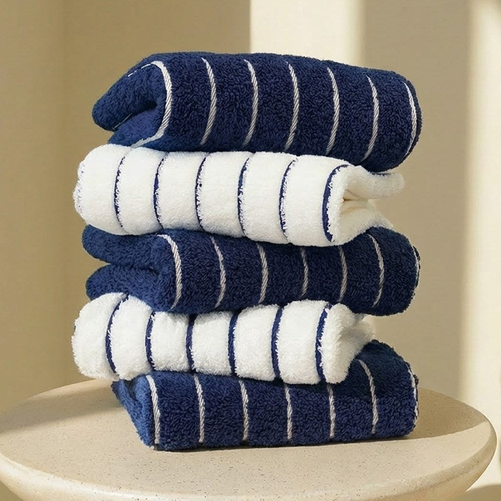 Towel Talk Seacline face towels in navy and white stripes, stacked on a round pale display table